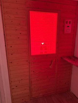 Wooden sauna door with a warm red glow inside illuminating the interior