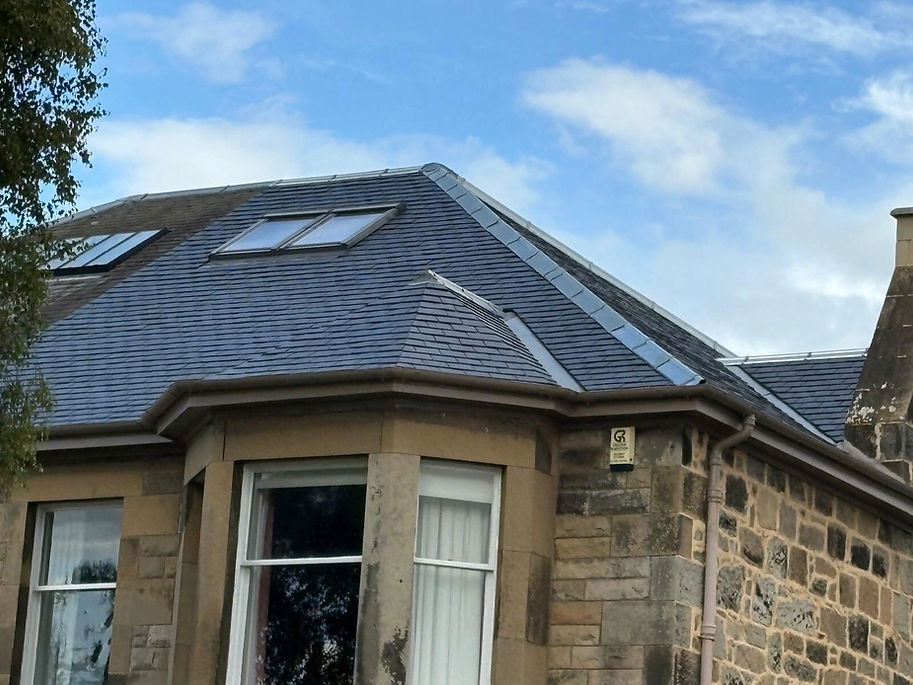 Stone house with a slate hipped roof, featuring skylights