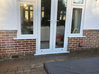 A white patio door with windows is set in a brick wall