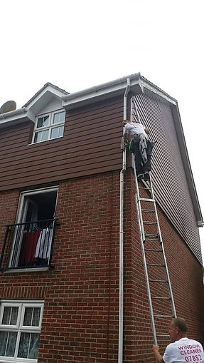 Roofer on a ladder carrying out roof replacement work on a residential house