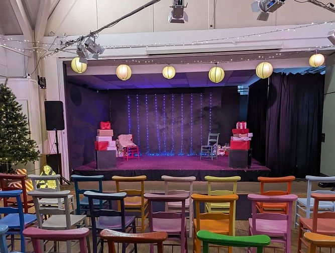 Lit theatre stage setup with chairs and props prepared for drama production