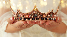 Close up view of hands holding an ornate metallic crown prop