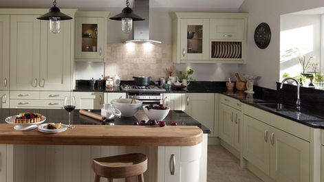Sage green kitchen cabinetry utilizing black granite counters and a central island.