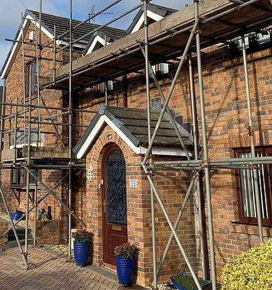 Close up view of steel tube scaffolding structures erected around the brick porch entryway of a building