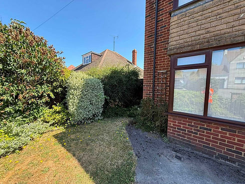 Mown garden lawn beside a brick house with well maintained hedges
