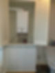 A white water heater is mounted on a bathroom wall with shuttered doors