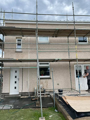 A man works on a house's exterior with scaffolding in place