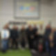 A group of people stands smiling inside a gym next to a wall with “Coach Ian Willows Strength & Conditioning” on it
