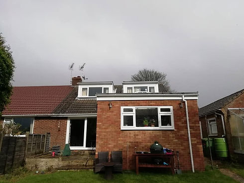 Rear exterior view of a brick house showing roofline dormer windows and guttering