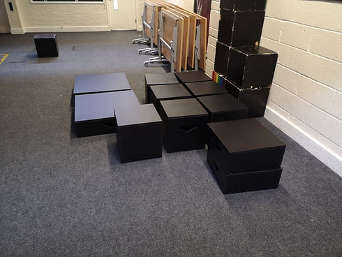 Multiple black wooden rehearsal boxes arranged on carpeted floor