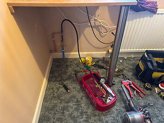 Plumbing tools electronic diagnostic equipment and loose wires arranged on a work surface during repairs