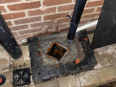 Close up view of an external black plastic waste pipe connected near a brick house wall