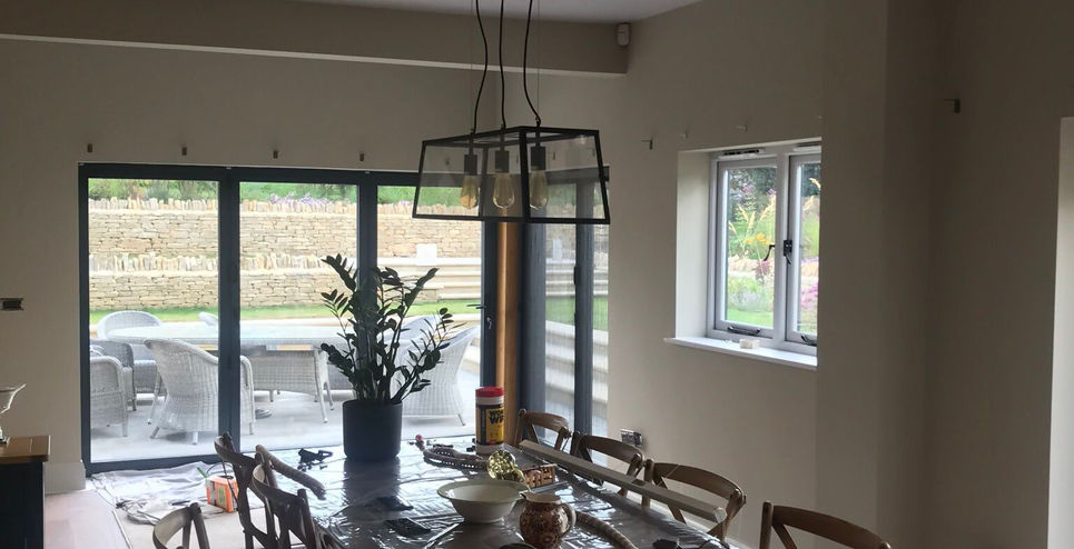 Spacious dining room featuring a long wooden table and chairs, with large glass doors looking out onto a patio