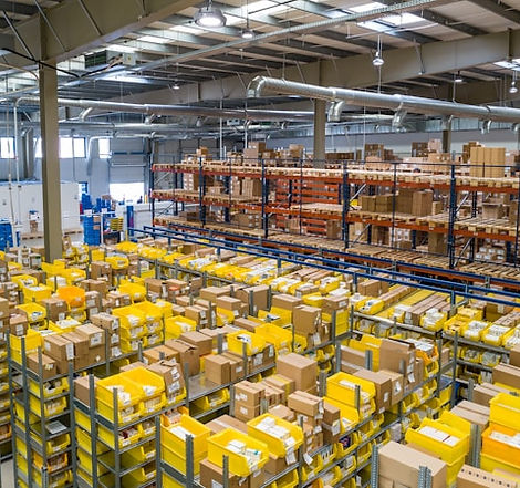 A bustling warehouse filled with organized shelves and yellow bins