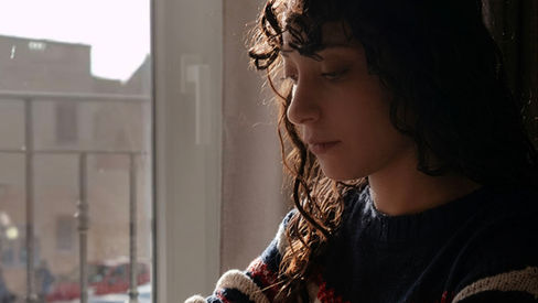 A girl doing calligraphy in front of a balcony.