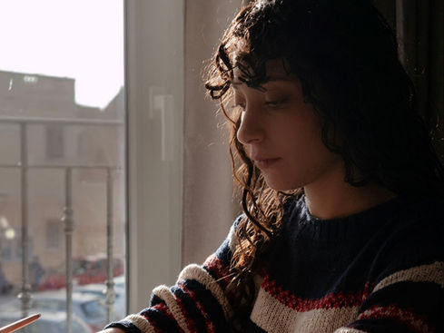 A girl doing calligraphy in front of a balcony.