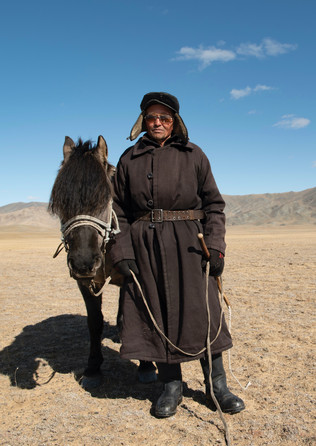 I asked this nomad man for directions and complimented him on his hat and outfit. He liked this. When I asked for the picture, he insisted that I take it with his horse.
"I will look better", he said "Trust me."
I was able to give him a printed copy of the picture before we left him.
You can see his herd in the background.
- Western Mongolia.