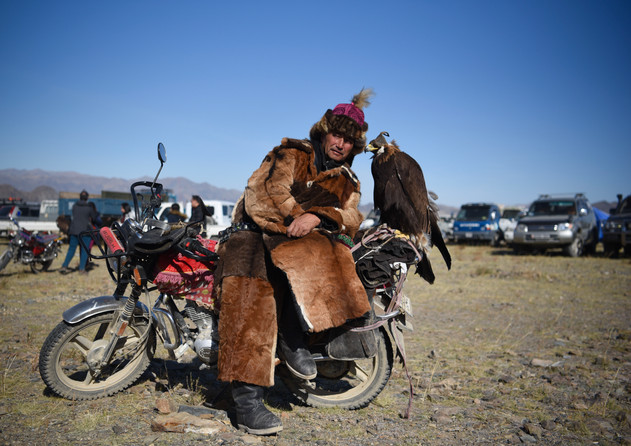 An eagle hunter poses with his bird and bike at the Golden Eagle Festival.
- Ölgii, Mongolia.