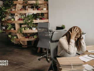 Mujer estresada sobre su escritorio con las manos en la cabeza, y con burnout.