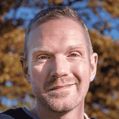 Author Upton Rand, smiling in a candid outdoor shot, close up.