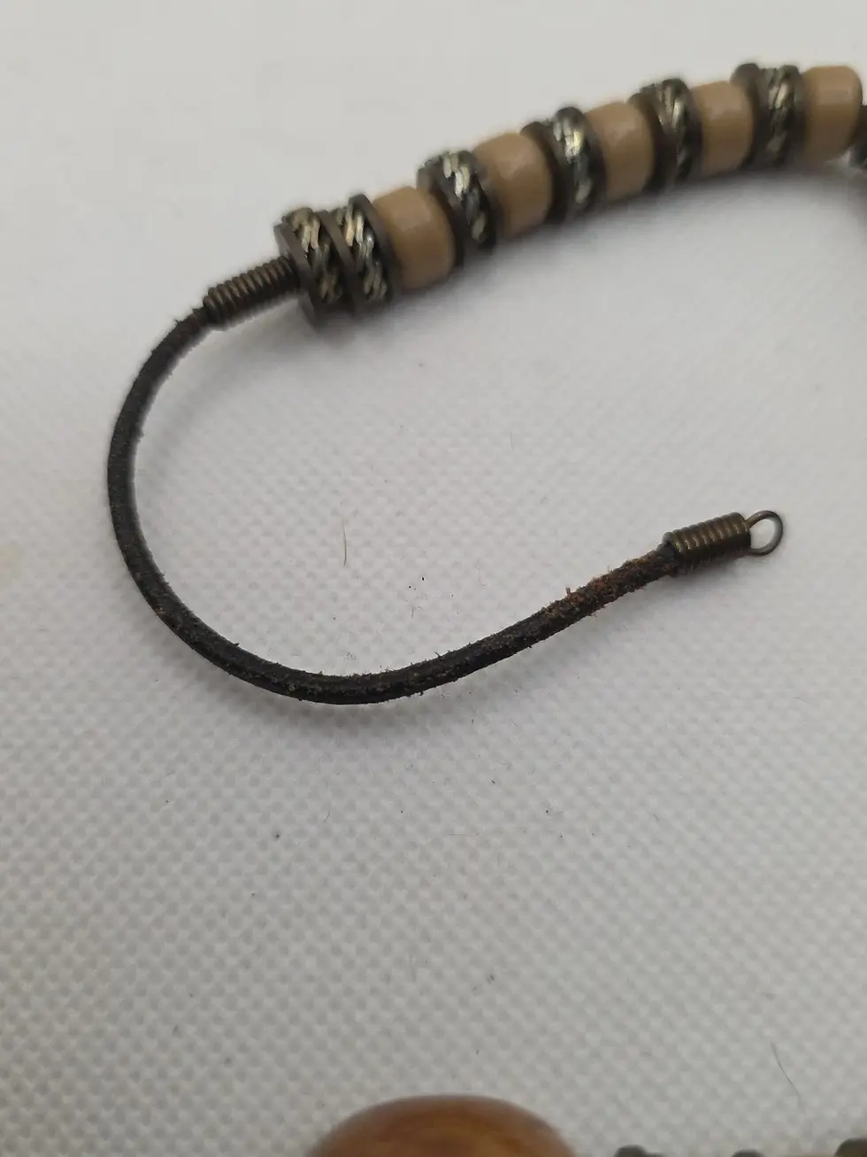 Thumbnail: Beaded jewelry with light beads, metal spacers, dark cord, and clasp