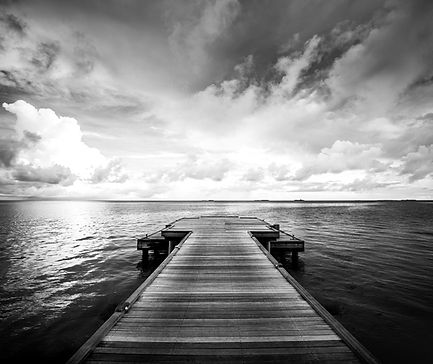 Wooden pier extending into the sea under a cloudy sky Sebesta Somatics Llc