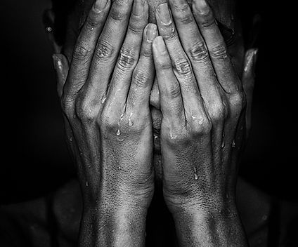 Person hiding face with wet hands in black and white close-up.