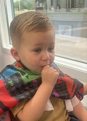 Jeune garçon avec une coupe de cheveux, suçant son pouce.