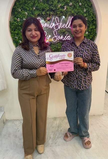 Two women holding a pink certificate at Bombshell by Sonia