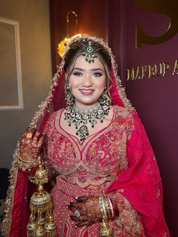 Smiling bride in red lehenga, intricate gold jewelry, and kalire