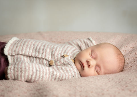 Babyfotografering af nyfødt liggende på lyserødt tæppe
