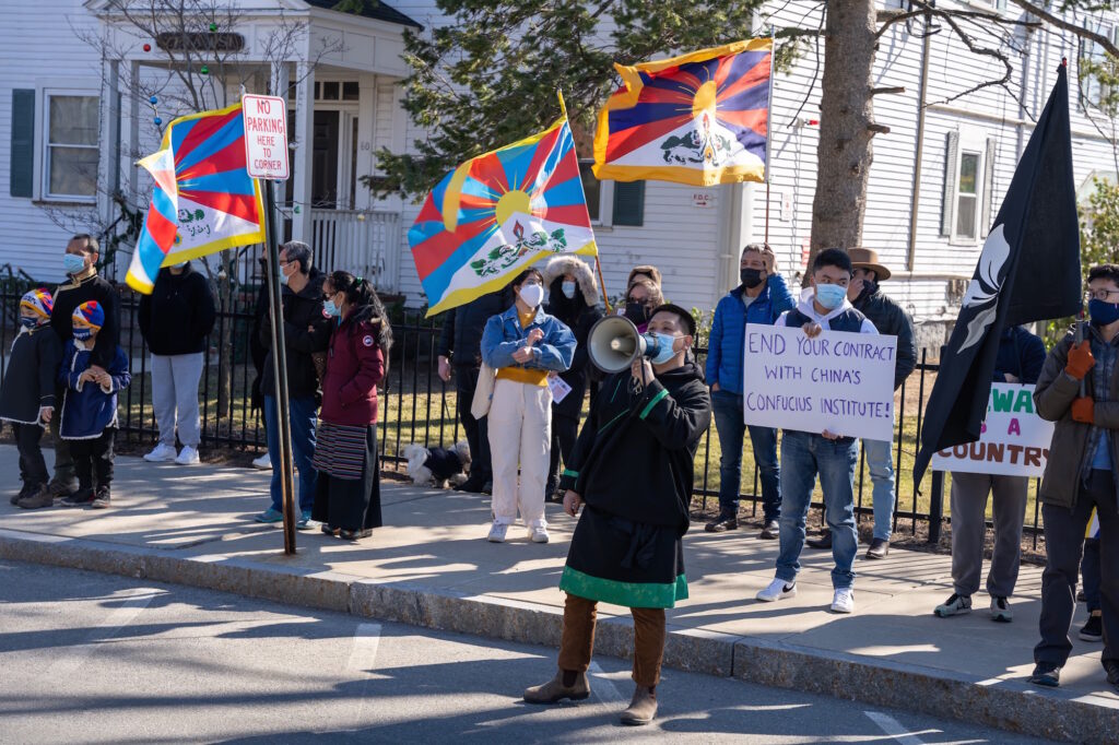Protesters line up with flags and signs to call for the shut down of the Confucius Institute at Tufts
