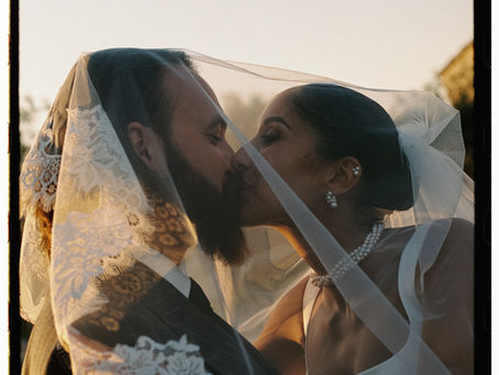 Una pareja besándose bajo un velo, una fotografía en color de 35 mm tomada por Caroline Marchante, fotógrafa de bodas