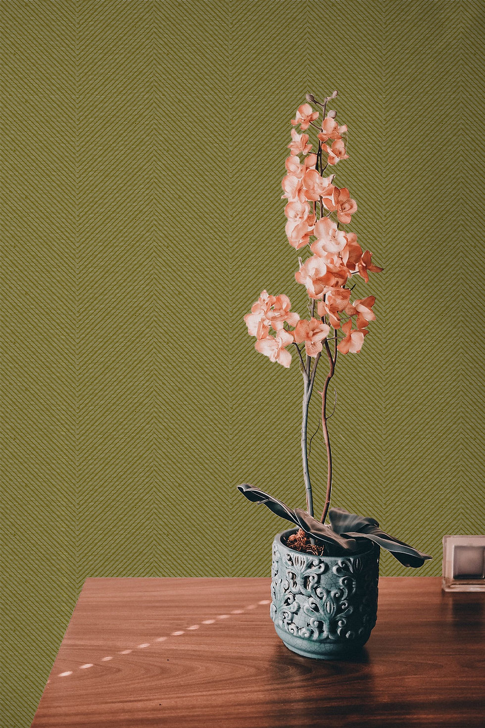 Pink potted plant against lime green herringbone wallcovering