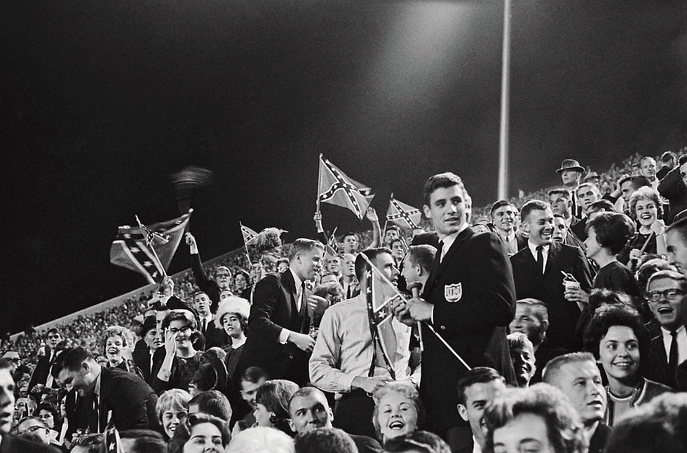 Students waving Confederate flags at the University of Mississippi football game in Jackson, Mississippi, the night before segregationists rioted over the enrollment of James Meredith, a black student. Photograph by Marion Trikosko, 29 September 1962.