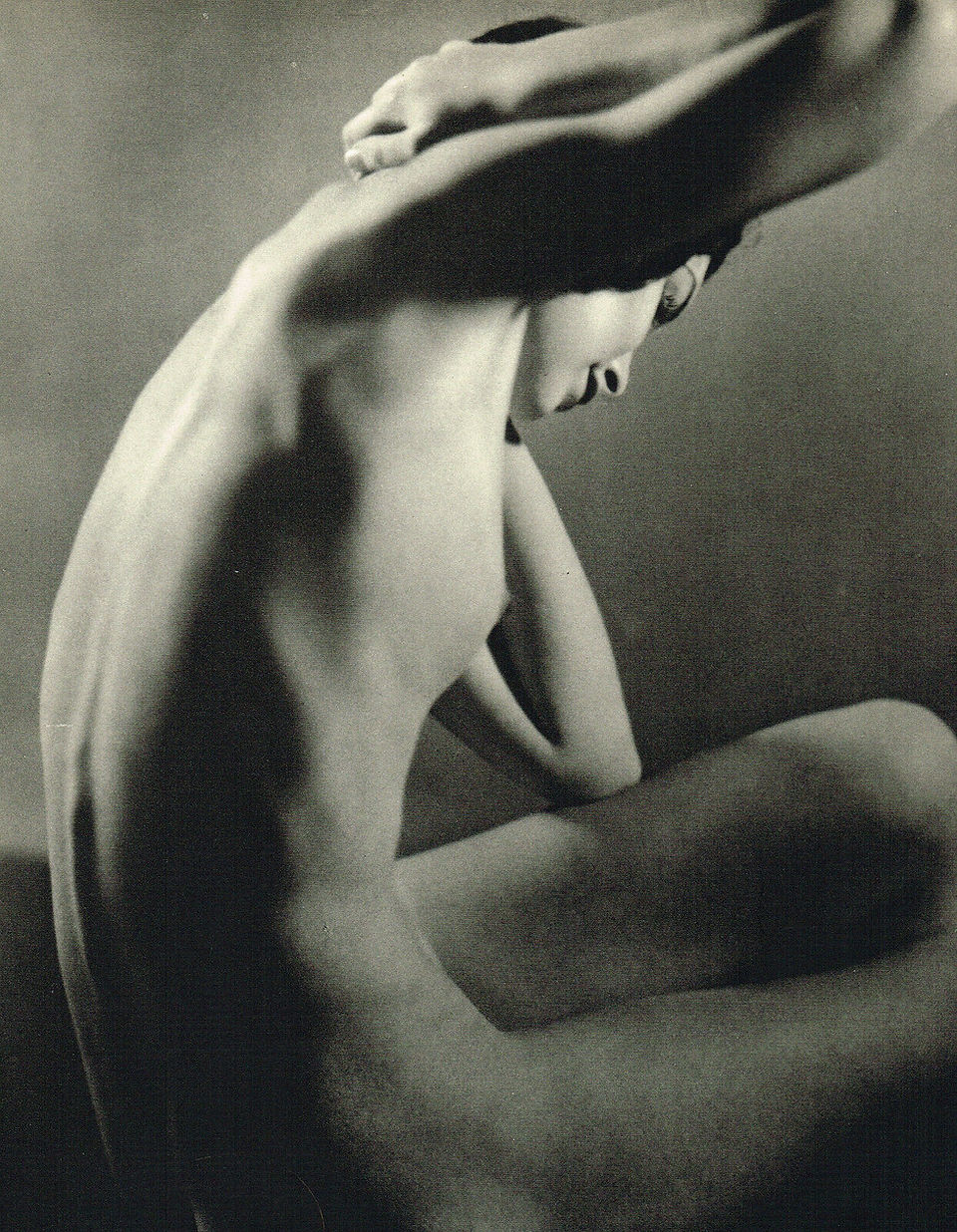 Artistic black and white photograph of a nude figure, back arched.