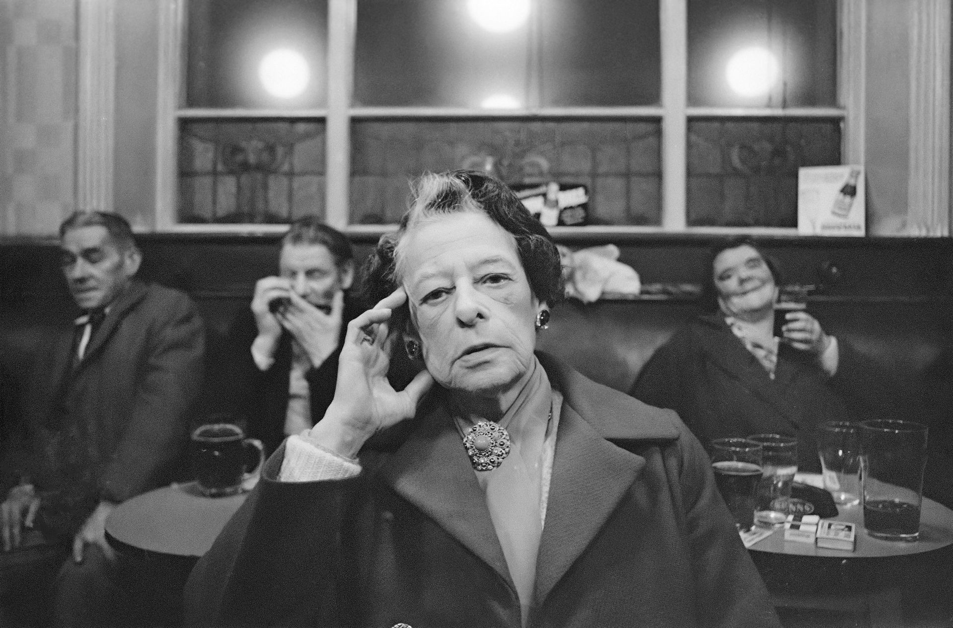 Serious older woman, light streak in hair, hand on temple, in cafe.