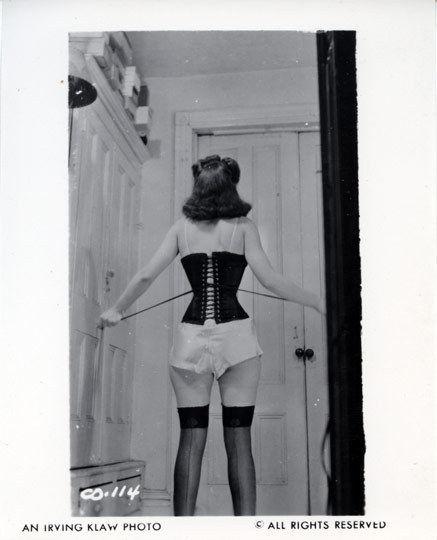 Woman from behind in black corset, white shorts, and stockings.