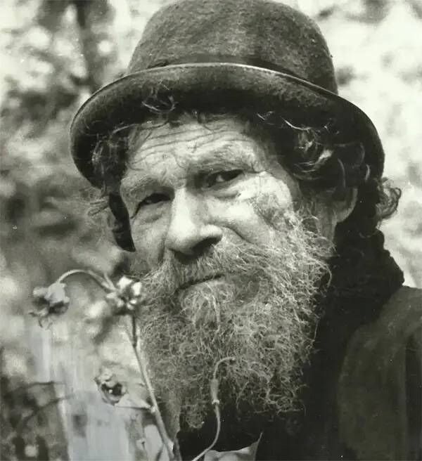 Man with thick beard, hat, looking directly forward, black and white.