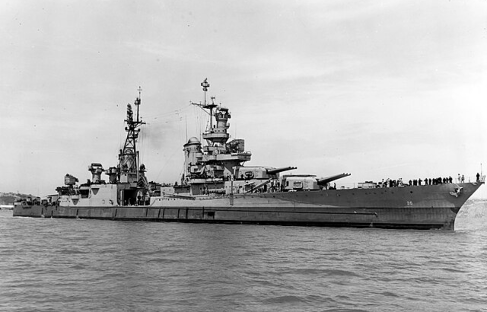 Battleship at sea with crew on deck, large guns visible. Calm water, clear sky, ship marked with "35" near the bow.