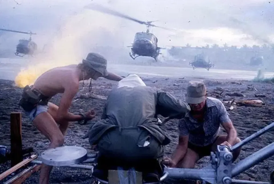 Soldiers preparing for helicopters approaching a dusty field.
