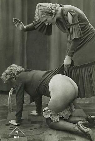 Bent woman's skirt lifted by another, exposing buttocks for discipline.