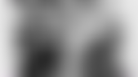 A man with a beard stands among armed men in turbans brandishing rifles and swords. They appear defiant in a sunlit wooded area.