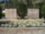 Gravestones for Oona and Charles Chaplin surrounded by vibrant flowers and greenery. The scene is serene and peaceful.
