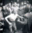 A woman and a man dance energetically in the center of a cheering crowd. Black and white setting with joyful expressions and lively atmosphere.