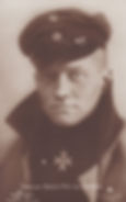Portrait of the Red Baron wearing a military cap and coat, with a solemn expression. An Iron Cross is displayed on his chest. Sepia tone.