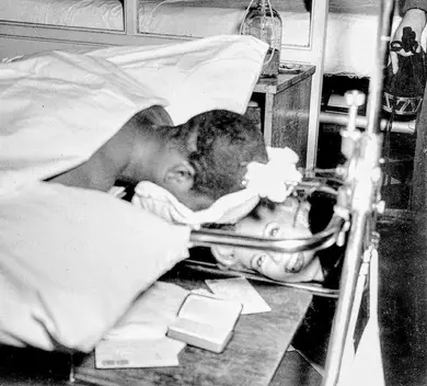 Person on a gurney, covered, another head on white pillow.