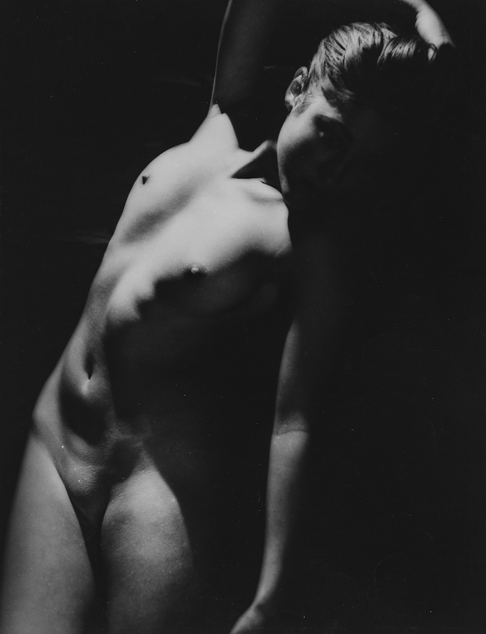 Dramatic black and white photo of a lean, bare human torso.