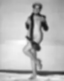 A woman poses with a large snake draped around her in a neutral-toned room. She wears gloves and heels, exuding confidence. No text visible.