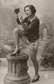 Woman posing suggestively, leg on pedestal, showing stocking and garter.